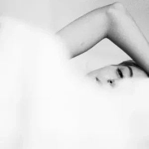 lady with her hand over her head under a duvet
